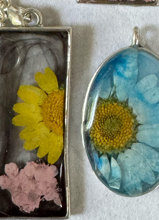 Photograph of several pendants and earrings made from flowers and epoxy resin