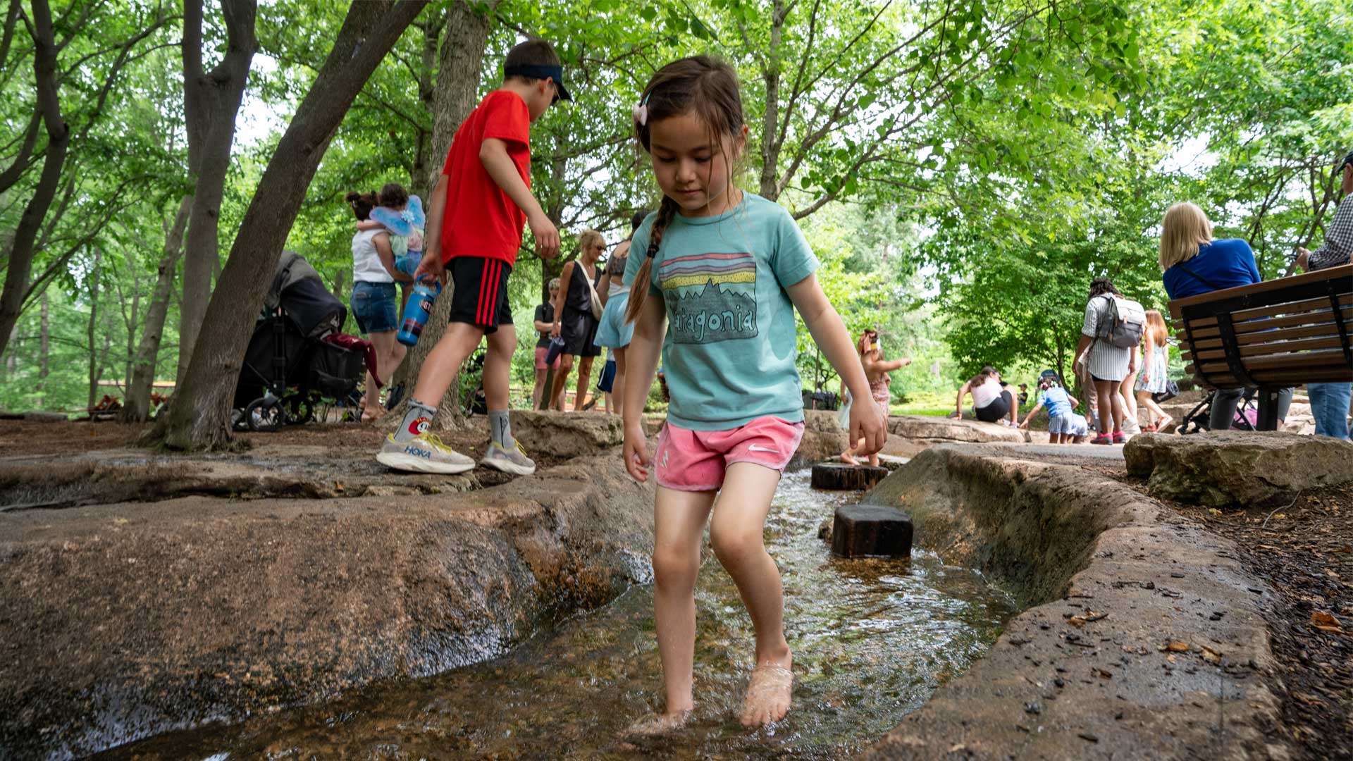 A child plays in a stream in the Children's Garden