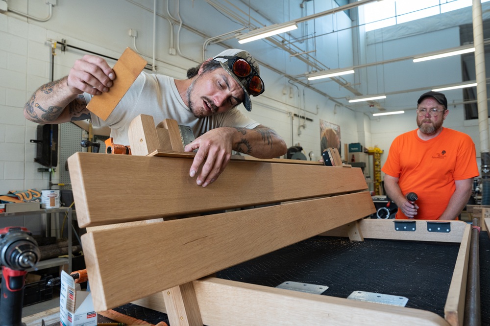 A carpenter checks angles while building a bench.