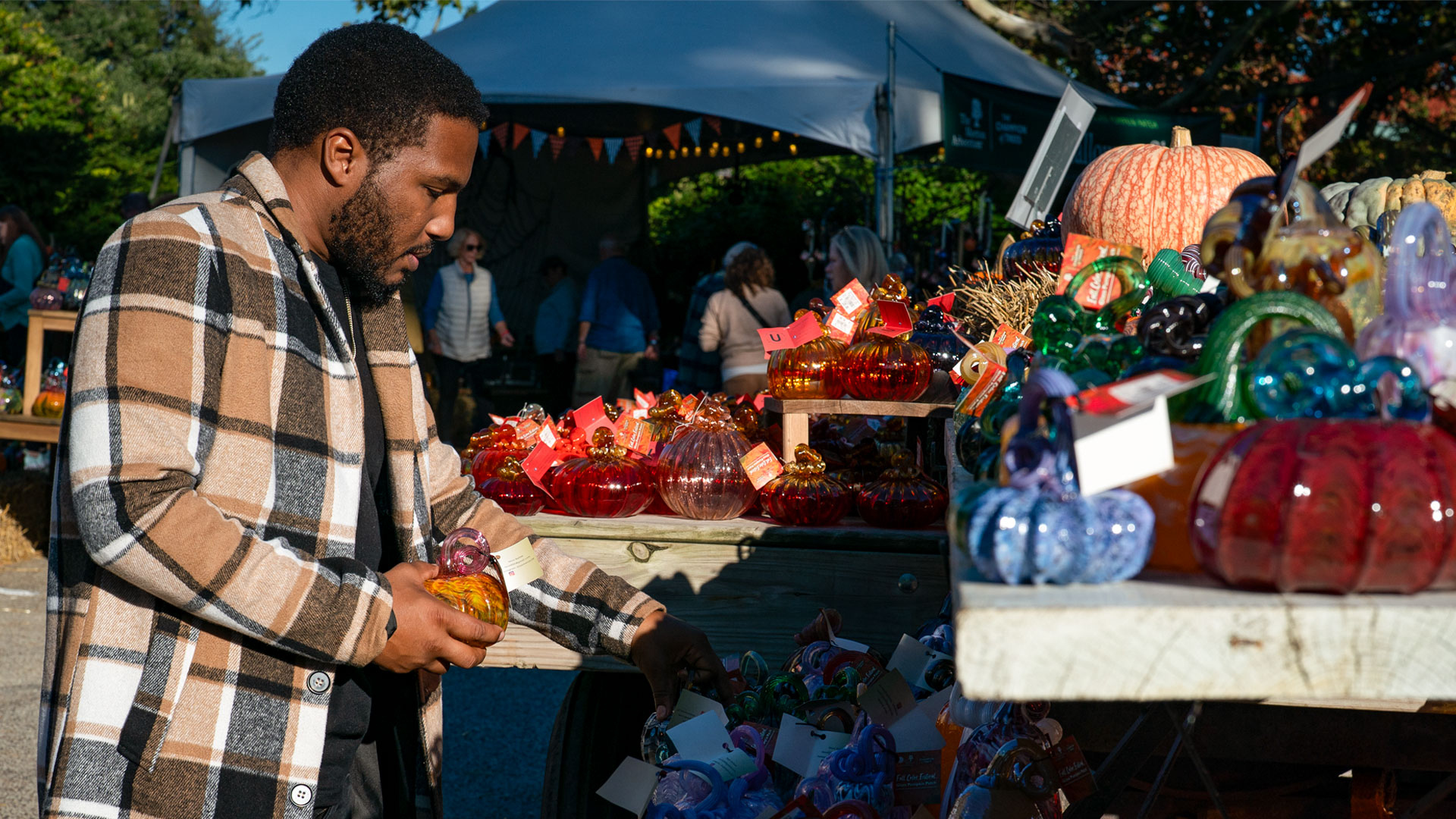 A man looks closely at all of the blown glass pumpkins