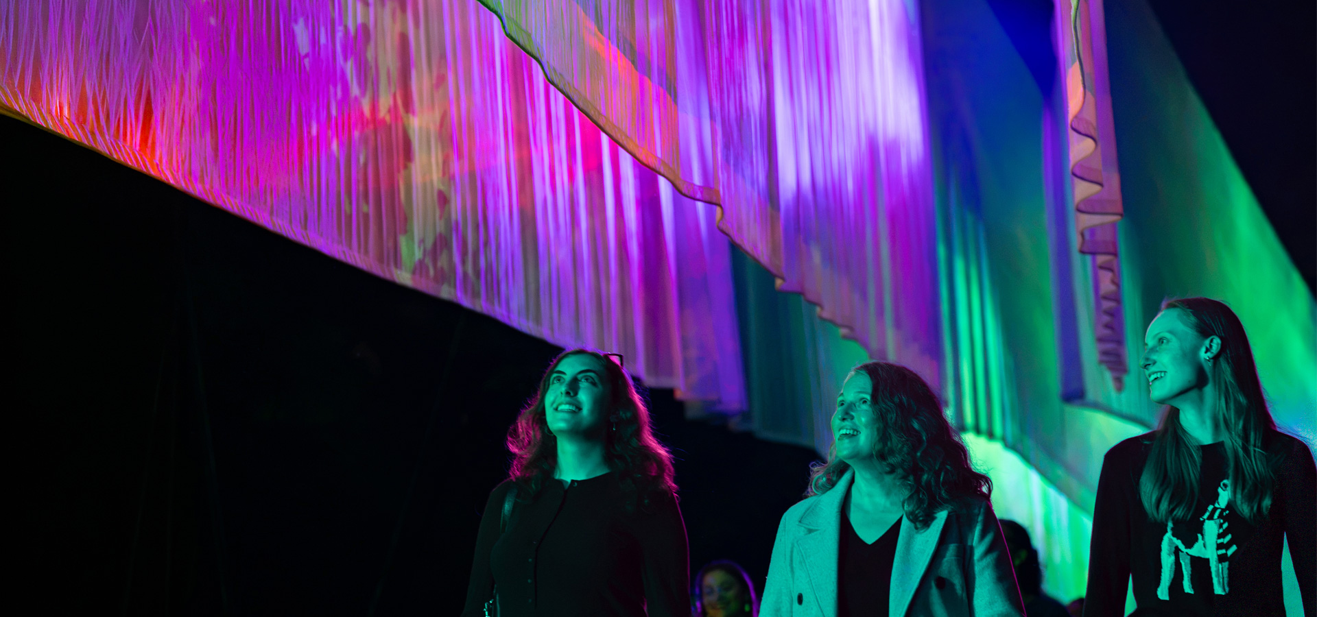 Guests walk next to the Northern Lights at Illumination
