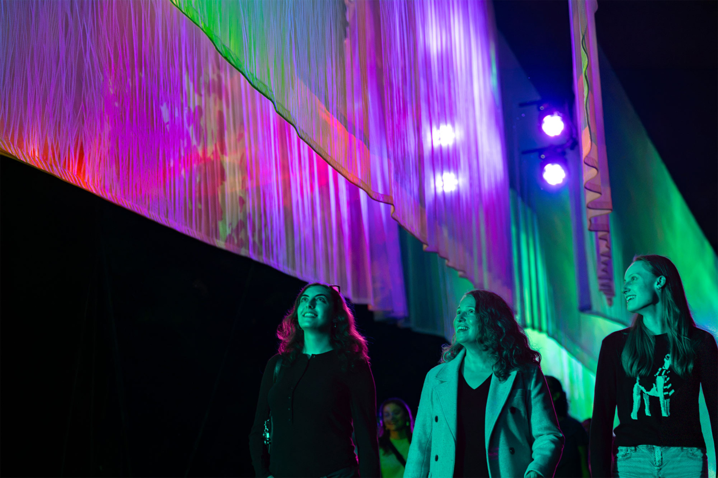 Guests walk next to the Northern Lights at Illumination