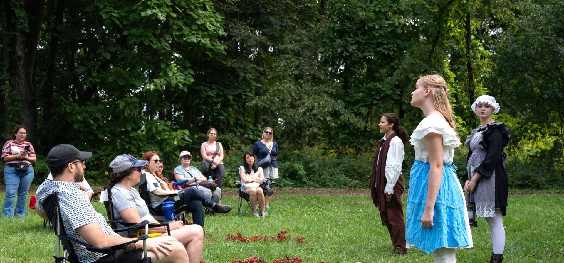 Actors portray a scene in Wuthering Heights for a crowd seated in folding chairs