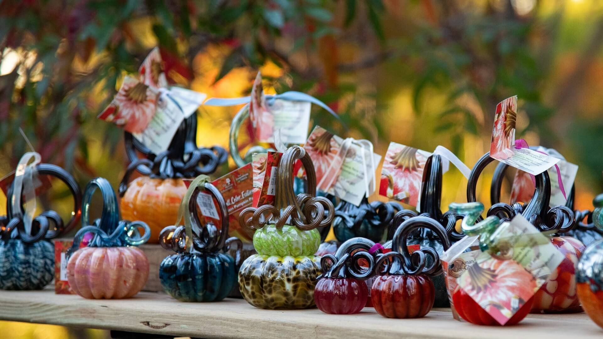 A selection of glass pumpkins set in front of autumn leaves